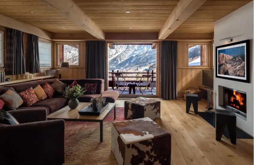 Sala de estar de chalé em Chamonix, com lareira, sofás confortáveis e uma varanda com vista para as montanhas nevadas