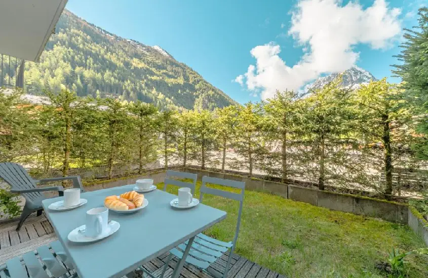 Mesa de café da manhã ao ar livre em um jardim com vista para as montanhas de Chamonix em um dia claro