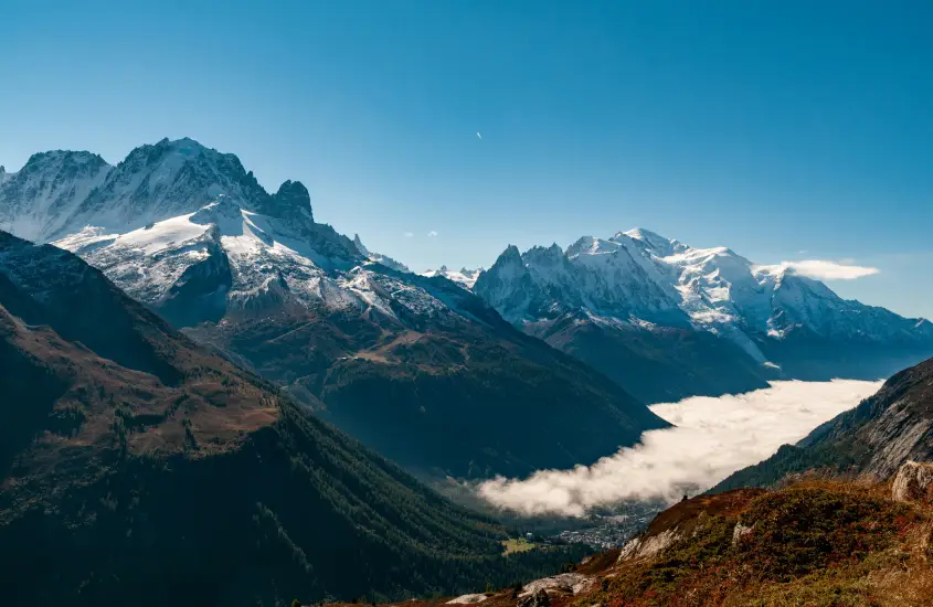 Vista panorâmica das montanhas de Chamonix sob um céu azul claro, com vales verdes abaixo