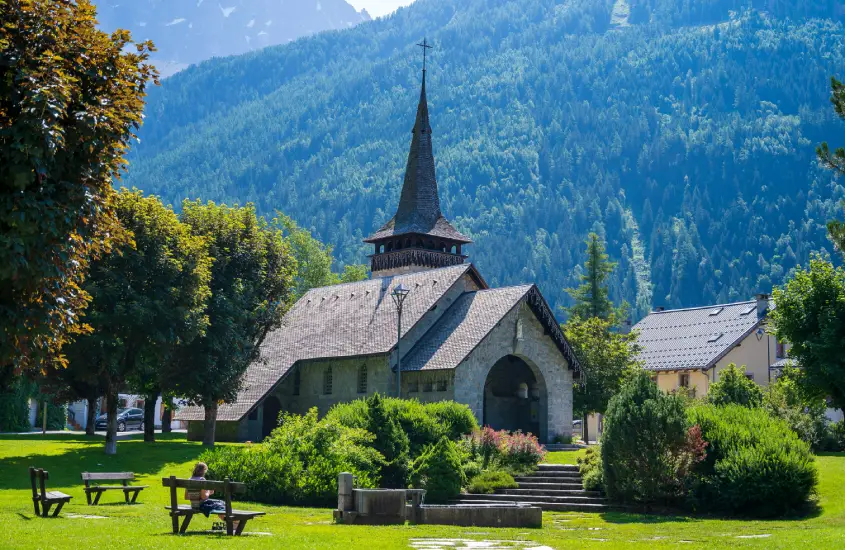 Igreja charmosa cercada por árvores e montanhas verdes em Chamonix, em um dia ensolarado