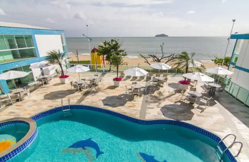 Área de piscina de hotel com vista para a praia, mostrando o ambiente familiar e acolhedor, perfeito para quem busca onde se hospedar para ir ao Beto Carrero