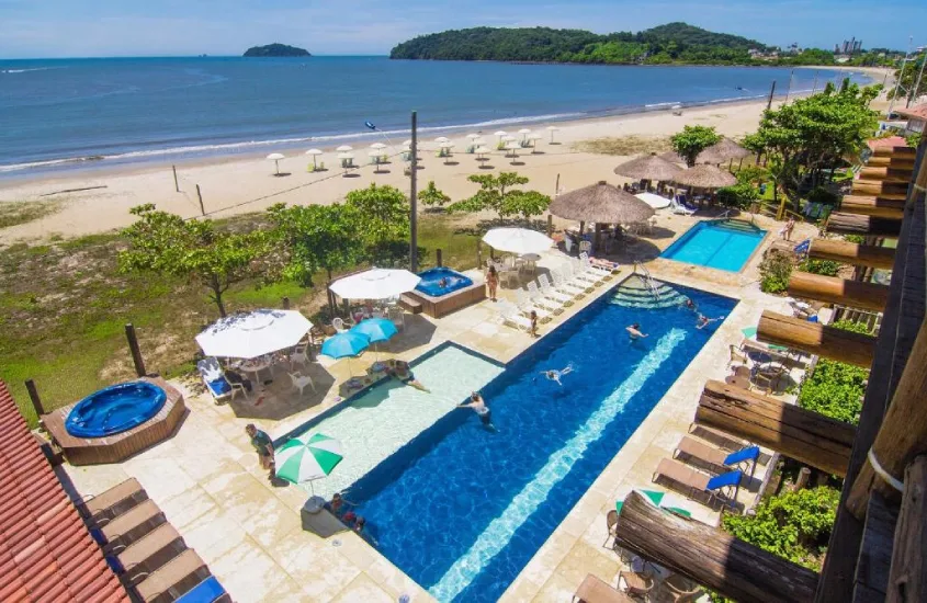 Vista aérea da pousada à beira-mar, com piscina e jacuzzis ao ar livre, perfeita para famílias que desejam aproveitar Penha e o Beto Carrero World