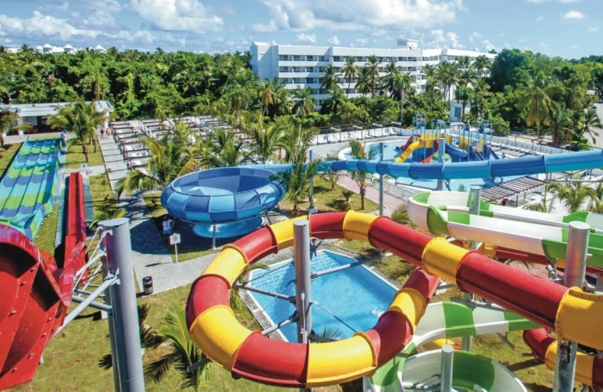 Vista aérea de resort à beira-mar com piscina central e várias áreas de lazer