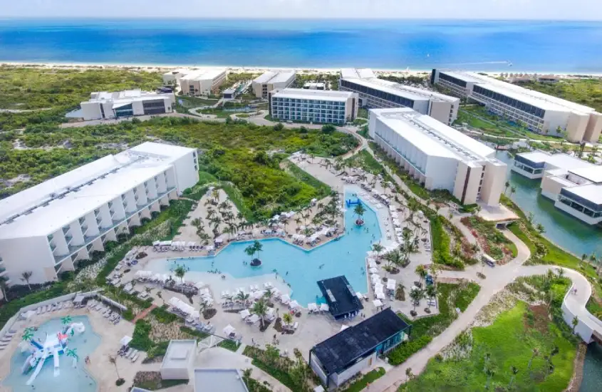 Vista aérea de resort no Caribe, com várias piscinas, áreas de lazer e acesso direto à praia