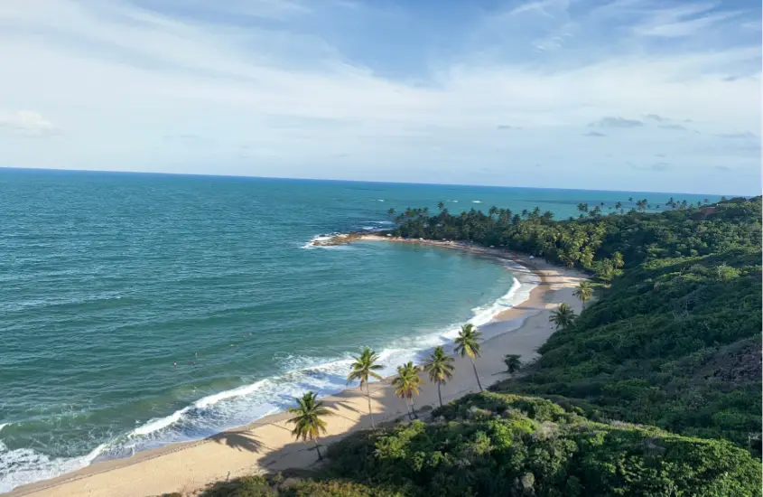 Praia deserta ao pôr do sol com um pequeno barraco à beira-mar e a água refletindo a luz dourada do sol