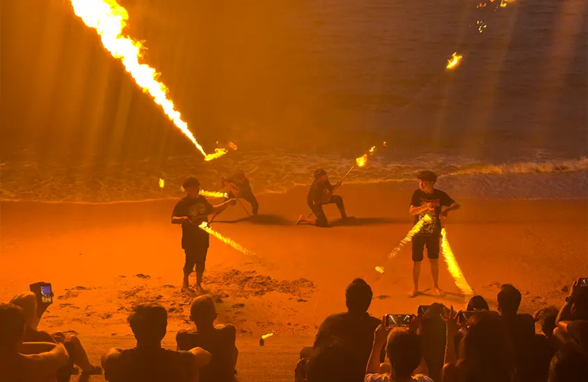 Espetáculo de fogos na praia de Koh Phi Phi à noite, com artistas manipulando fogo na areia