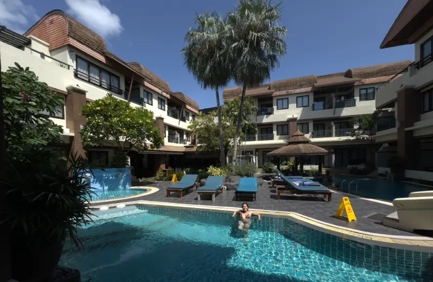 Área da piscina de um hotel em Koh Phi Phi, com hóspedes relaxando nas espreguiçadeiras e nadando na piscina durante o dia