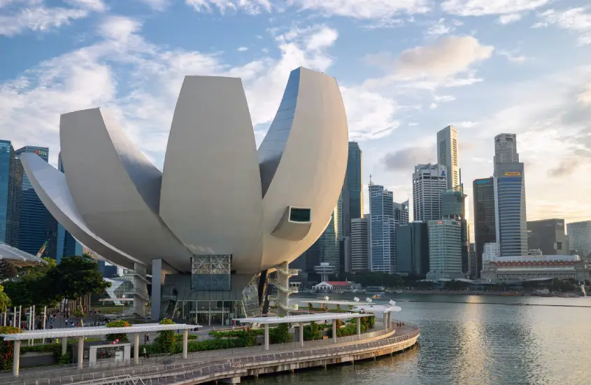 O ArtScience Museum, em Singapura, capturado ao entardecer, com prédios modernos ao fundo e céu parcialmente nublado.