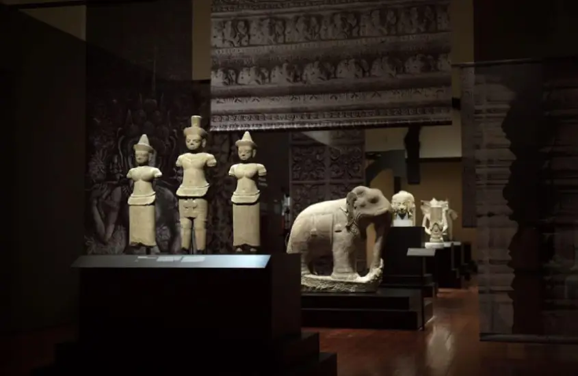 Exposição de esculturas e artefatos no Asian Civilisations Museum, Singapura, em uma sala com iluminação suave.