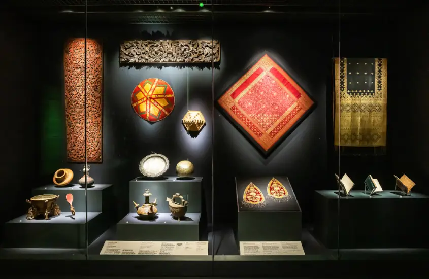 Exposição de artefatos culturais, incluindo tecidos e objetos decorativos, no Peranakan Museum, Singapura.