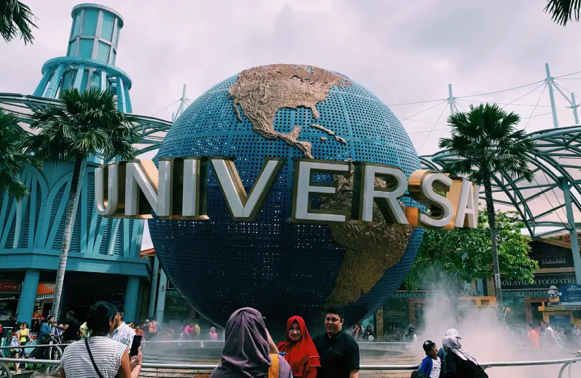 Entrada da Universal Studios Singapore com o globo terrestre e pessoas ao redor durante o dia.