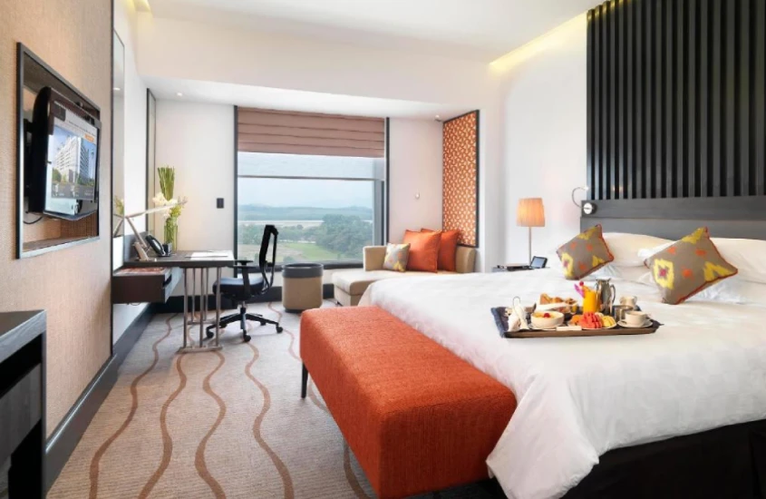 Quarto de hotel moderno com cama grande, mesa de trabalho e vista para a área externa no Sama Sama Hotel KLIA