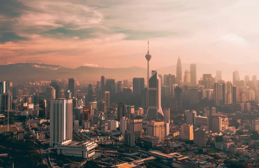 Panorama da cidade de Kuala Lumpur ao pôr do sol, destacando o horizonte e a Torre de Kuala Lumpur