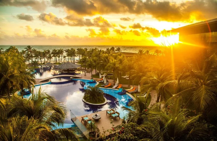 Piscina do Carmel Cumbuco Resort ao pôr do sol, com as últimas luzes do sol refletindo na água