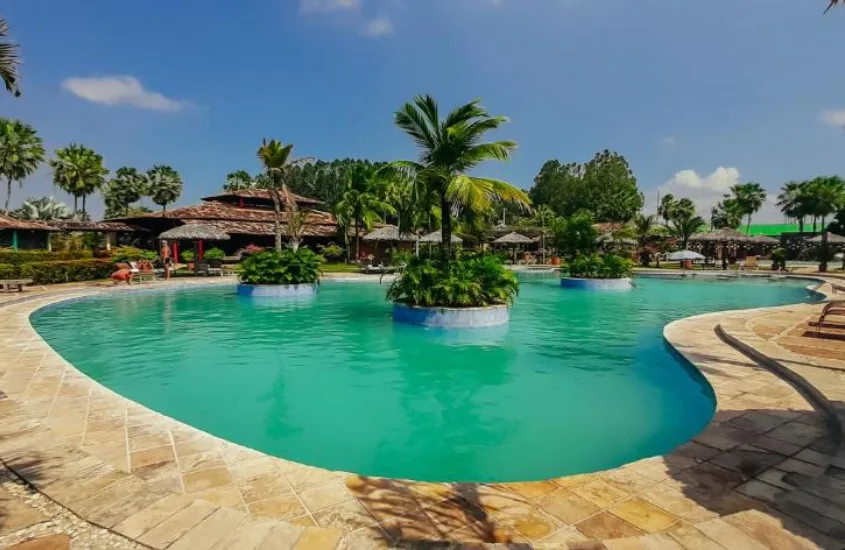 Piscina de resort de luxo no Brasil durante o dia, rodeada por vegetação tropical e espreguiçadeiras