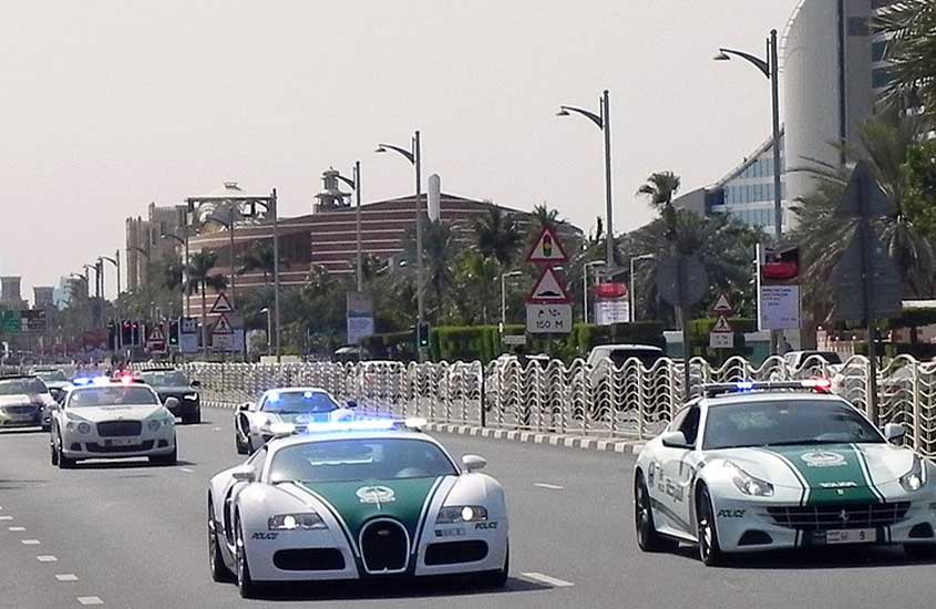 Uma linha de carros de polícia de alta velocidade, incluindo um Bugatti, em uma rua de Dubai.