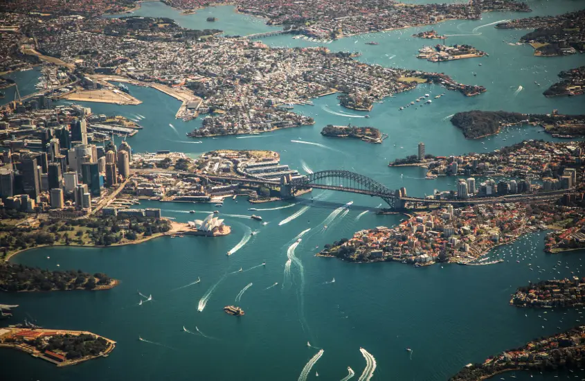 Vista aérea da cidade de Sydney com a icônica Sydney Opera House, Harbour Bridge e barcos no porto. Uma das vistas mais famosas da Austrália