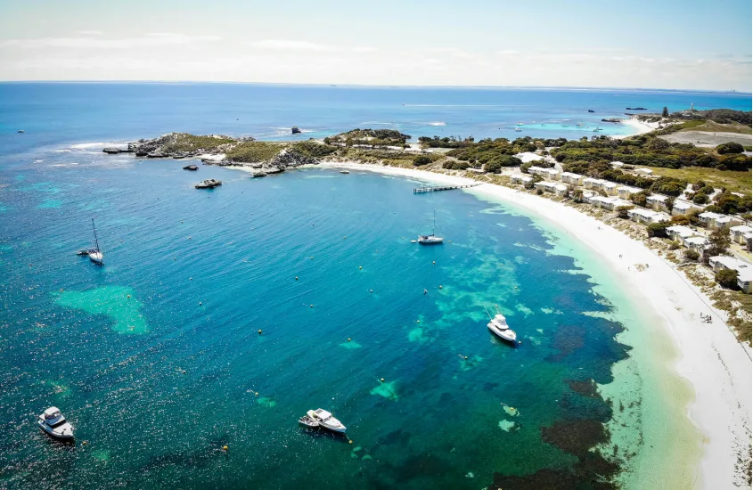 Vista aérea de uma praia australiana com águas cristalinas e barcos ancorados, um paraíso costeiro típico da Austrália