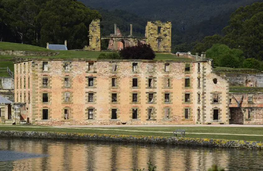 Ruínas históricas de uma antiga prisão australiana em Port Arthur, refletidas em águas calmas.