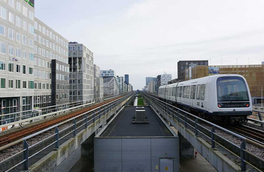 Trem moderno circulando em uma linha elevada em meio à cidade de Copenhague