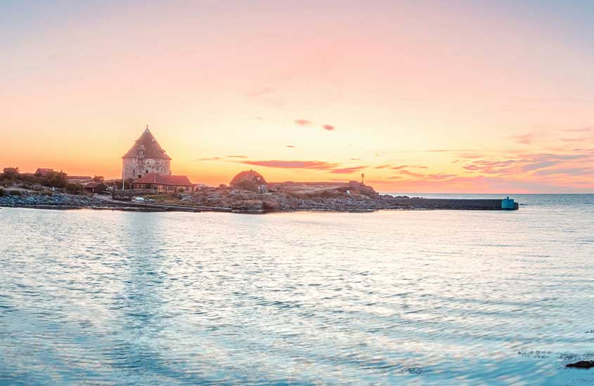 Vista panorâmica de um castelo histórico à beira do mar na Dinamarca ao pôr do sol