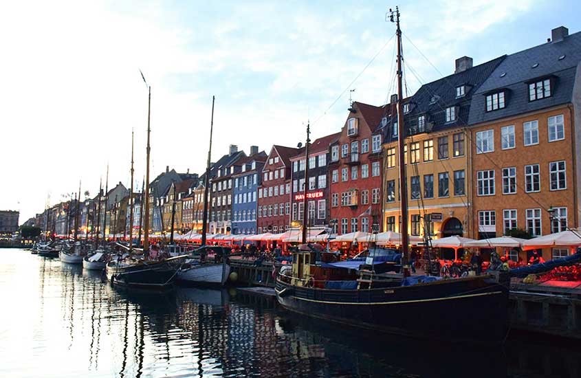 Barcos ancorados no canal Nyhavn, cercados por coloridos edifícios históricos, um dos pontos mais famosos de Copenhague