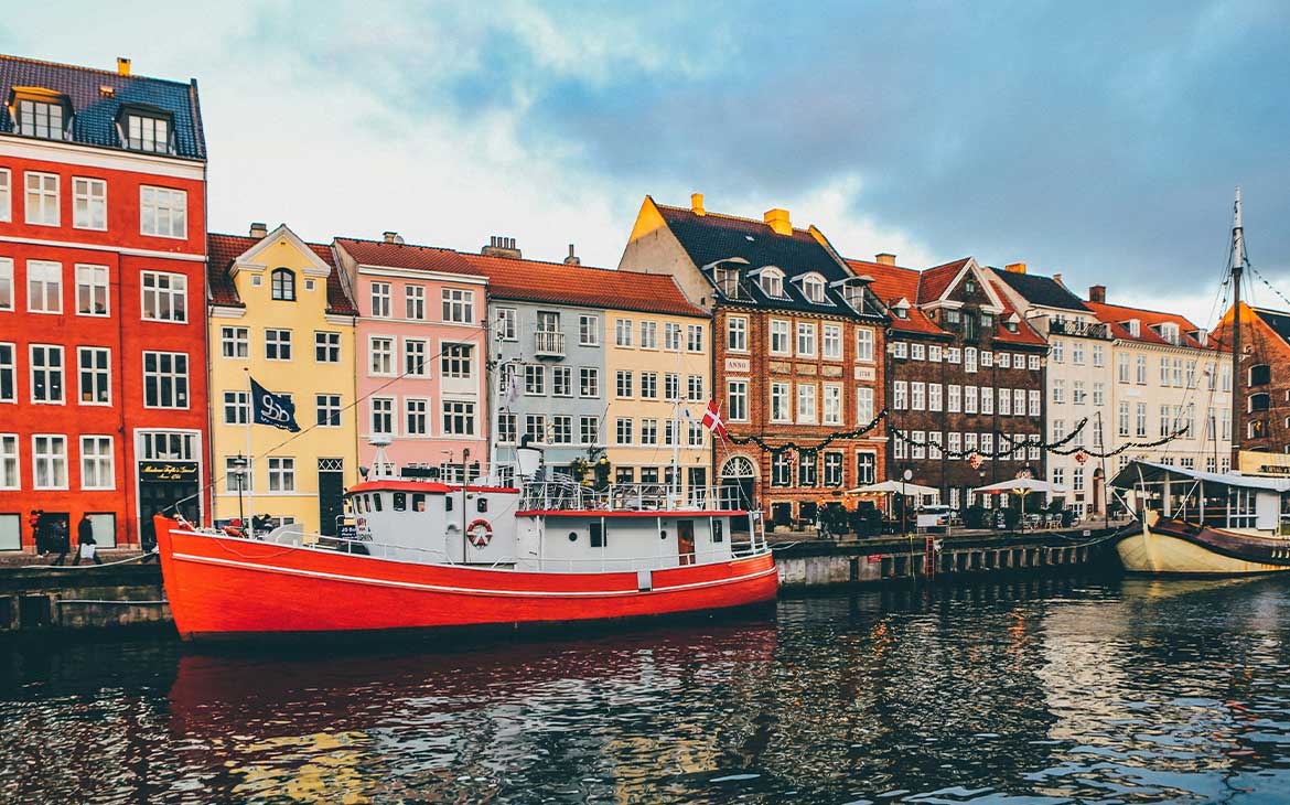 Um barco vermelho ancorado em frente aos edifícios coloridos no canal Nyhavn, uma das áreas mais conhecidas de Copenhague