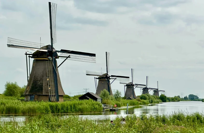 Moinhos de vento tradicionais de Kinderdijk em uma paisagem verde com céu parcialmente nublado, um dos símbolos da Holanda