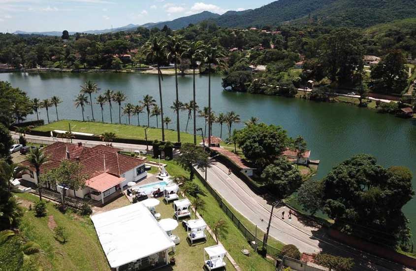 Vista aérea de Miguel Pereira, com lago, montanhas e uma propriedade de hotel ao lado da estrada