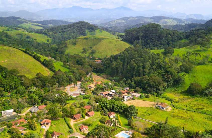 Área externa de um hotel fazenda em Santo Antônio do Pinhal, com chalés azuis e um lago ao redor