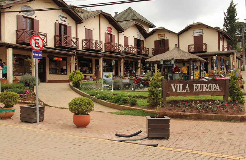 Charmosa vila de estilo europeu em Monte Verde, com casas de madeira e varandas floridas ao redor de uma pequena praça