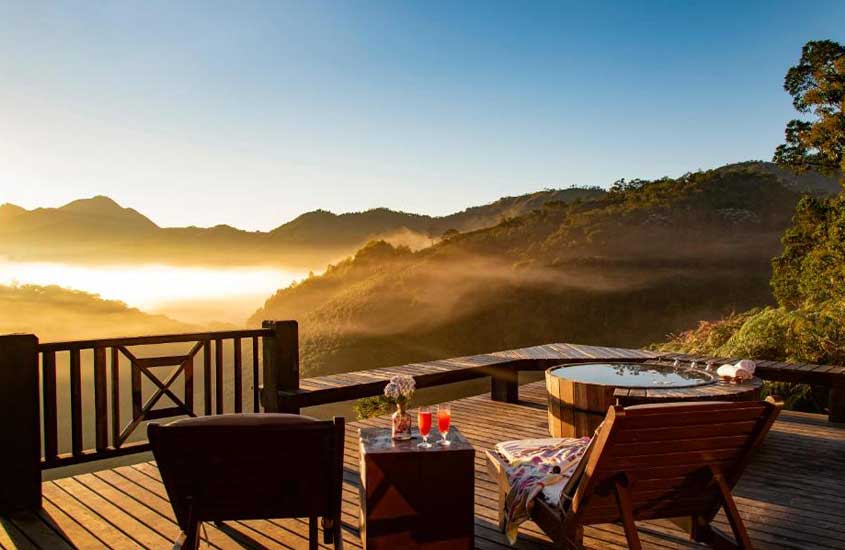 Deck de madeira em um hotel em Visconde de Mauá, com vista para montanhas cobertas de névoa ao amanhecer