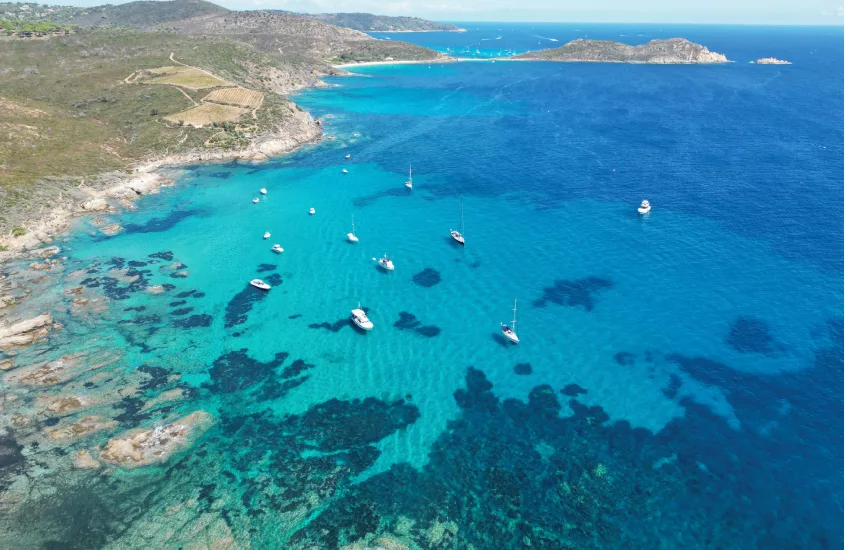 Vista aérea da costa rochosa e águas cristalinas com veleiros ancorados, em um dia claro em um dos destinos de praia na Europa