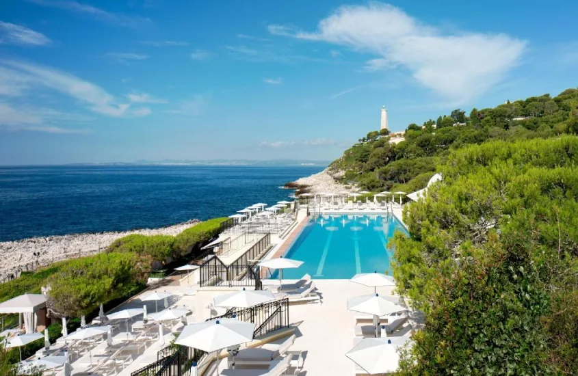 Piscina luxuosa à beira de um penhasco com vista para o mar azul no Grand-Hôtel du Cap-Ferrat em um dia ensolarado