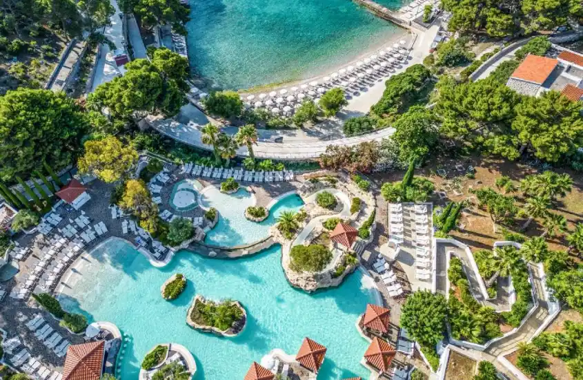 Vista aérea do Amfora Hvar Grand Beach Resort com várias piscinas e praia privada cercada por vegetação verde