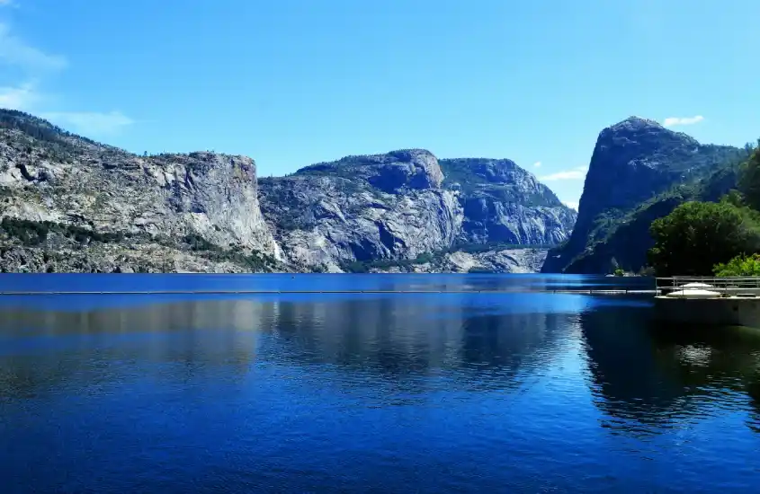 Um lago de águas azuis cercado por montanhas rochosas gigantescas sob um céu azul claro