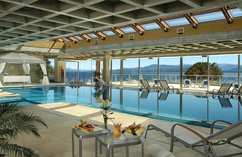 Piscina interna com vista panorâmica para o lago Nahuel Huapi no Cacique Inacayal Lake Hotel & Spa, um dos melhores resorts de inverno na América do Sul