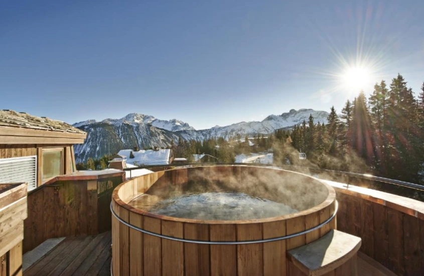 Banheira de hidromassagem ao ar livre com vista para os Alpes, durante um dia ensolarado