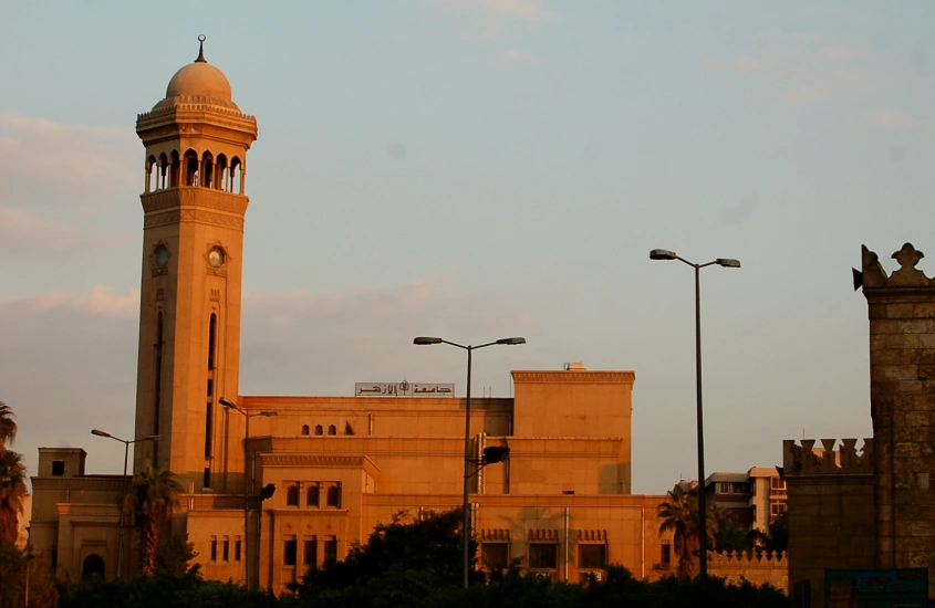 Estrutura imponente de uma mesquita egípcia ao pôr do sol, com a torre se destacando contra o céu suave.