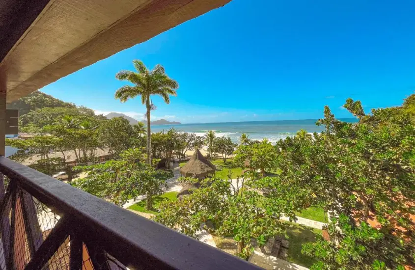 Vista da varanda de um quarto com palmeiras e o mar ao fundo, em um resort de frente para a Praia das Toninhas em Ubatuba.