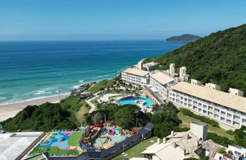 Vista aérea de um resort à beira-mar com parque aquático e área verde, capturada durante o dia