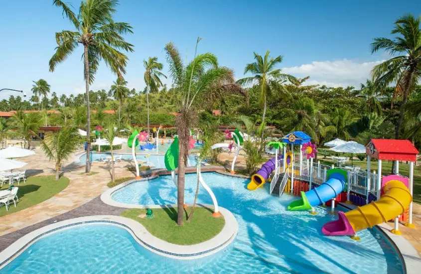 Piscina infantil com toboáguas e área de lazer ao ar livre no Salinas Maragogi All Inclusive Resort, rodeada por coqueiros.