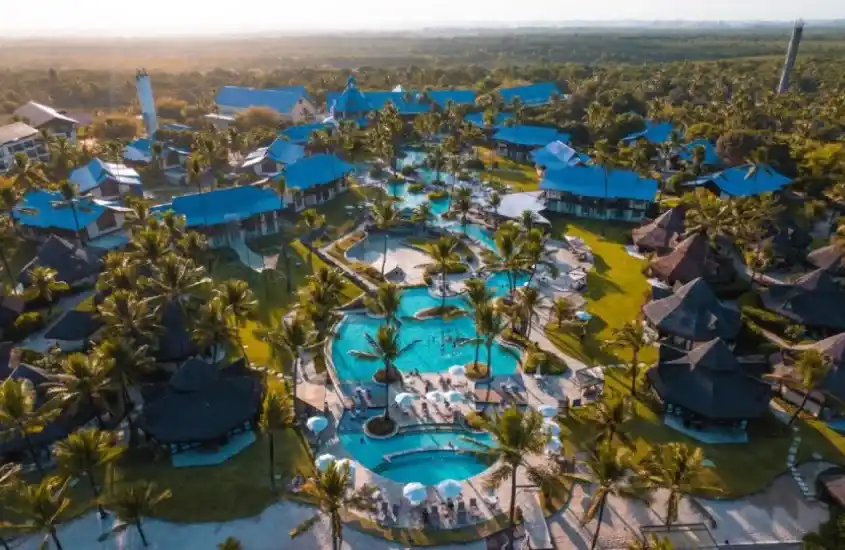 Vista panorâmica do Summerville Beach Resort, com piscinas rodeadas por coqueiros e jardins tropicais.