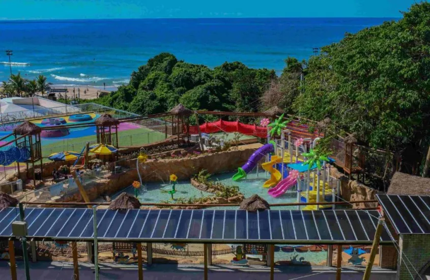 Vista aérea do parque infantil com toboáguas coloridos no Costão do Santinho Resort, com o mar ao fundo.