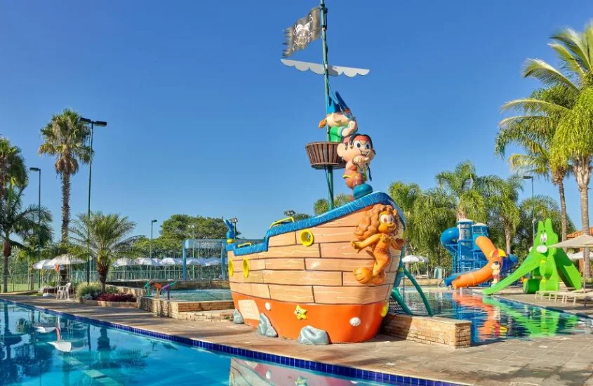 Barco temático em piscina infantil no Bourbon Resort Atibaia, com escorregadores e brinquedos em uma área arborizada.