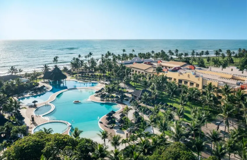 Piscina em formato orgânico com vista para o mar e rodeada de coqueiros no Iberostar Waves Bahia