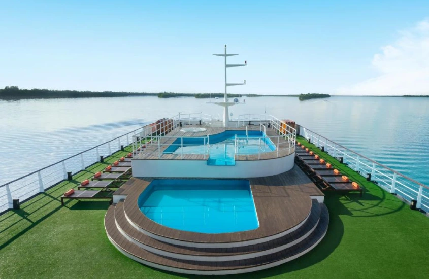 Piscinas ao ar livre no convés de um cruzeiro, com vista para as águas calmas do rio Amazonas, em um ambiente aberto e ensolarado.