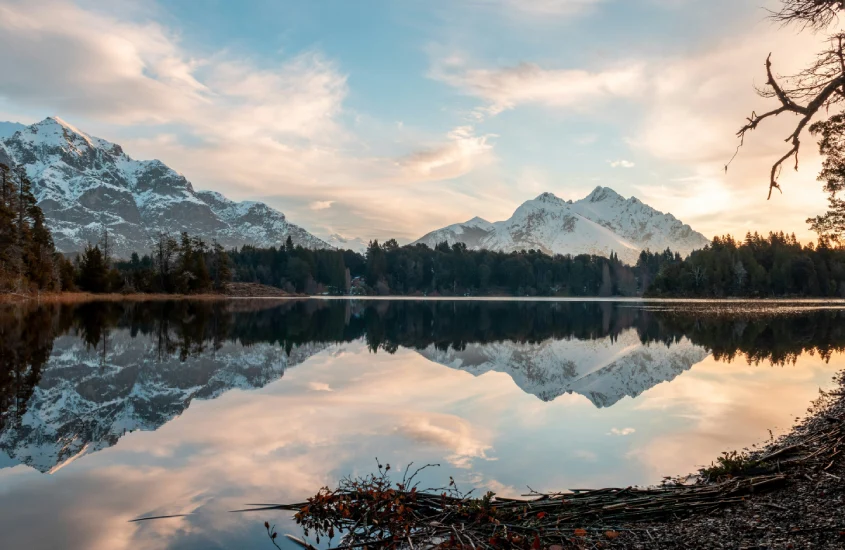 Paisagem refletida no lago em Bariloche, com montanhas cobertas de neve ao fundo