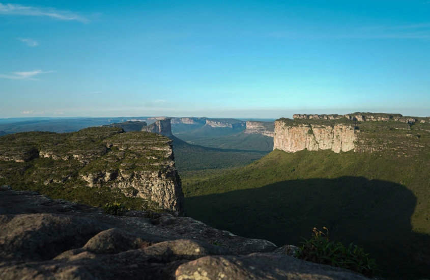 Paisagem da Chapada Diamantina com imensos paredões rochosos e vegetação verde ao longo das montanhas