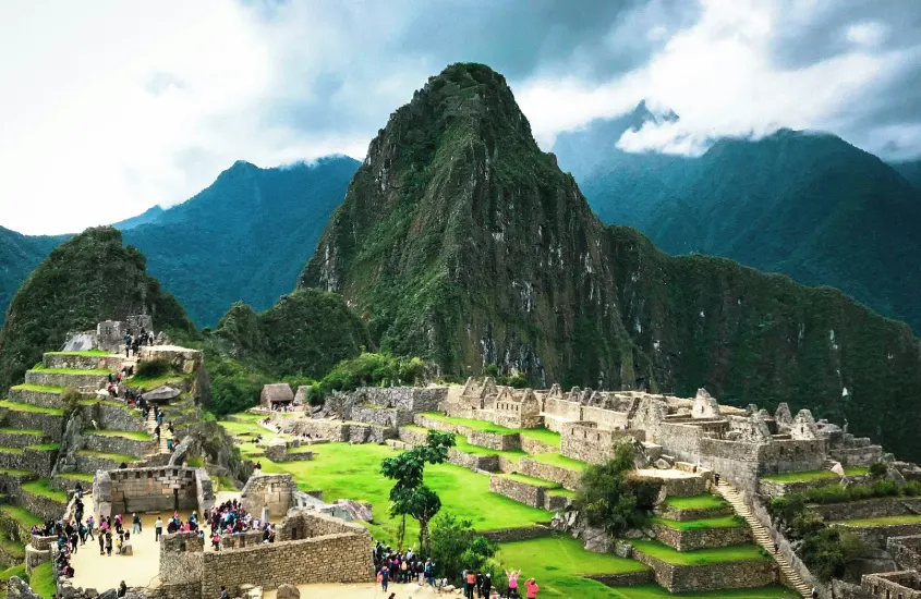 Ruínas de Machu Picchu com suas famosas construções de pedra ao redor de montanhas verdes e cobertas de neblina